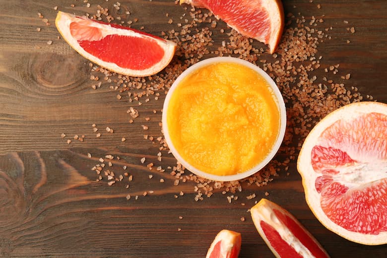 body scrub and grapefruit on wooden background